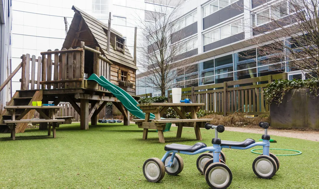 speeltuin kinderopvang met klimtoestel glijbaan fietsjes en picknicktafel