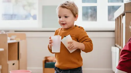 Peuter loopt met drinkbekers in hand