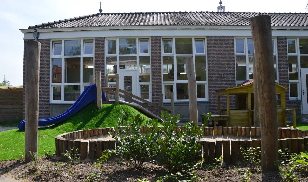 speeltuin kinderopvang met glijbaan en houten huisje