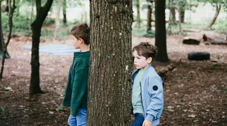 Twee jongens staan tegen boom aan in tuin