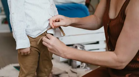 Vrouw doet broek aan bij peuter