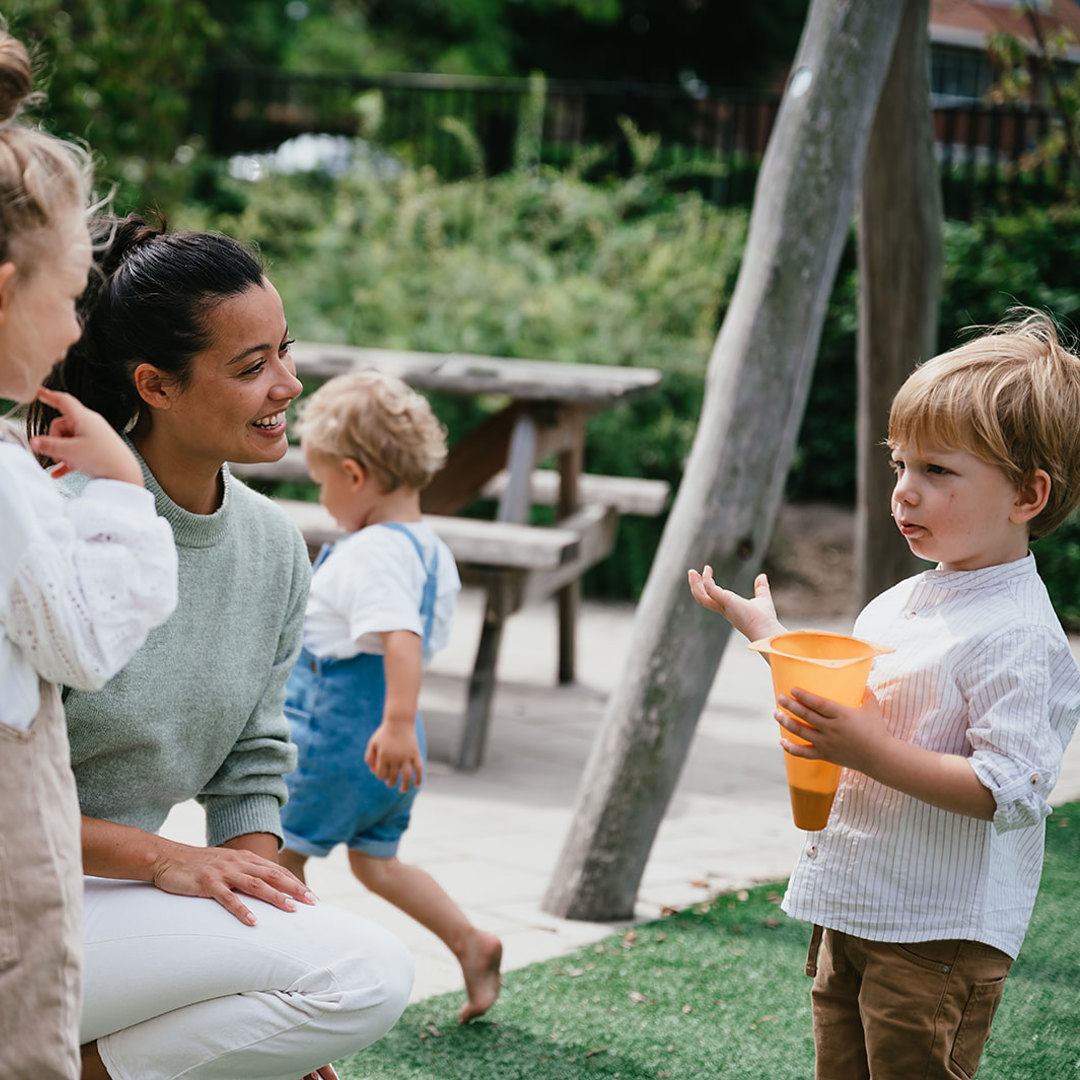 Pedagogisch Medewerker en kinderen spelen in tuin