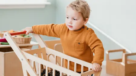 Peuter speelt met houten winkelwagen