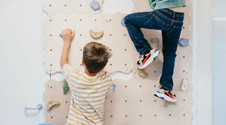 Twee jongen klimmen op een klimmuur