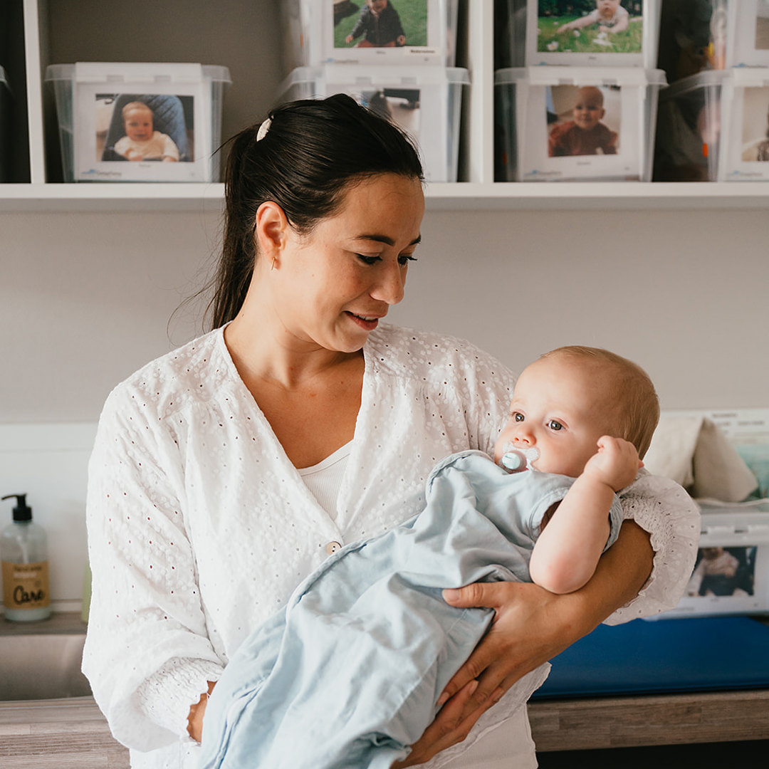 Pedagogisch Medewerker houdt baby vast