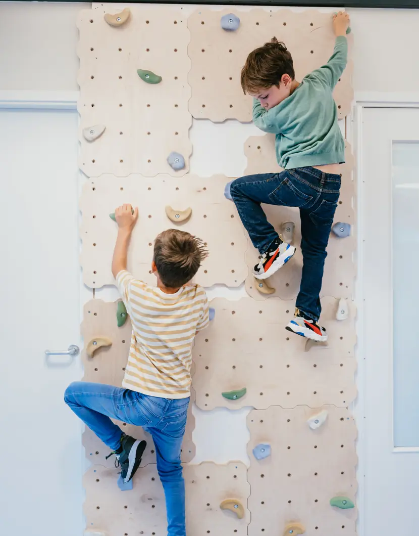 Twee jongen klimmen op een klimmuur