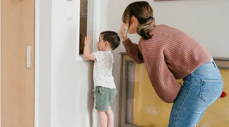 Peuter en Pedagogisch Medewerker zwaaien door het raam