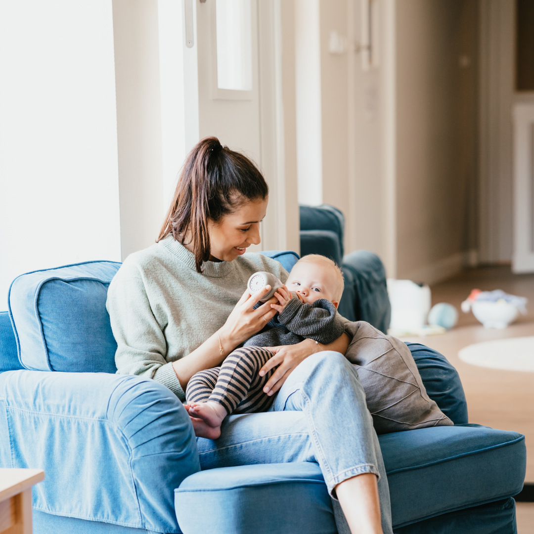 Vrouw geeft baby een fles op schoot