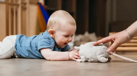 Baby speelt op de grond met knuffel