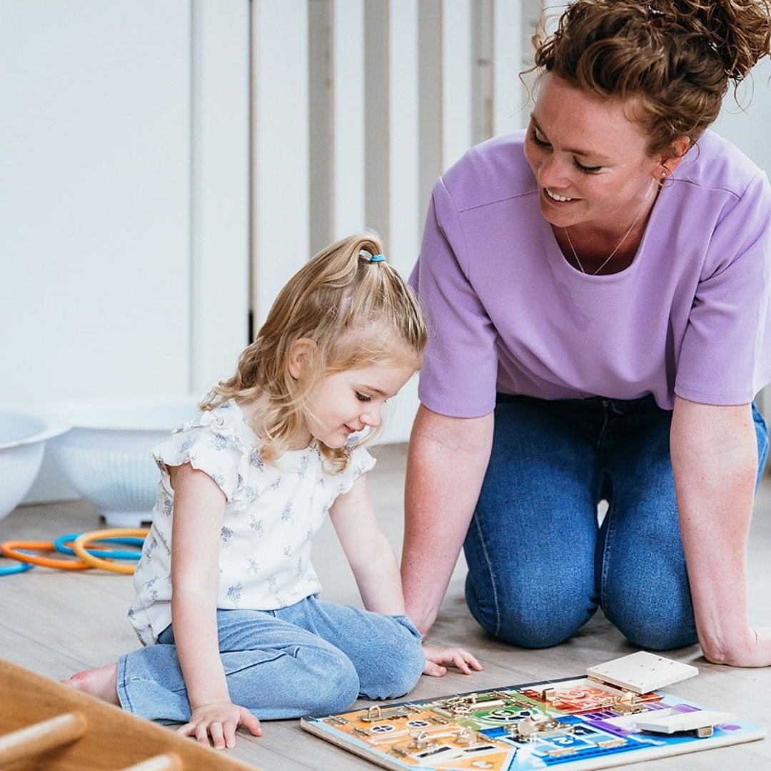 Meisje en vrouw doen samen een puzzel op de grond