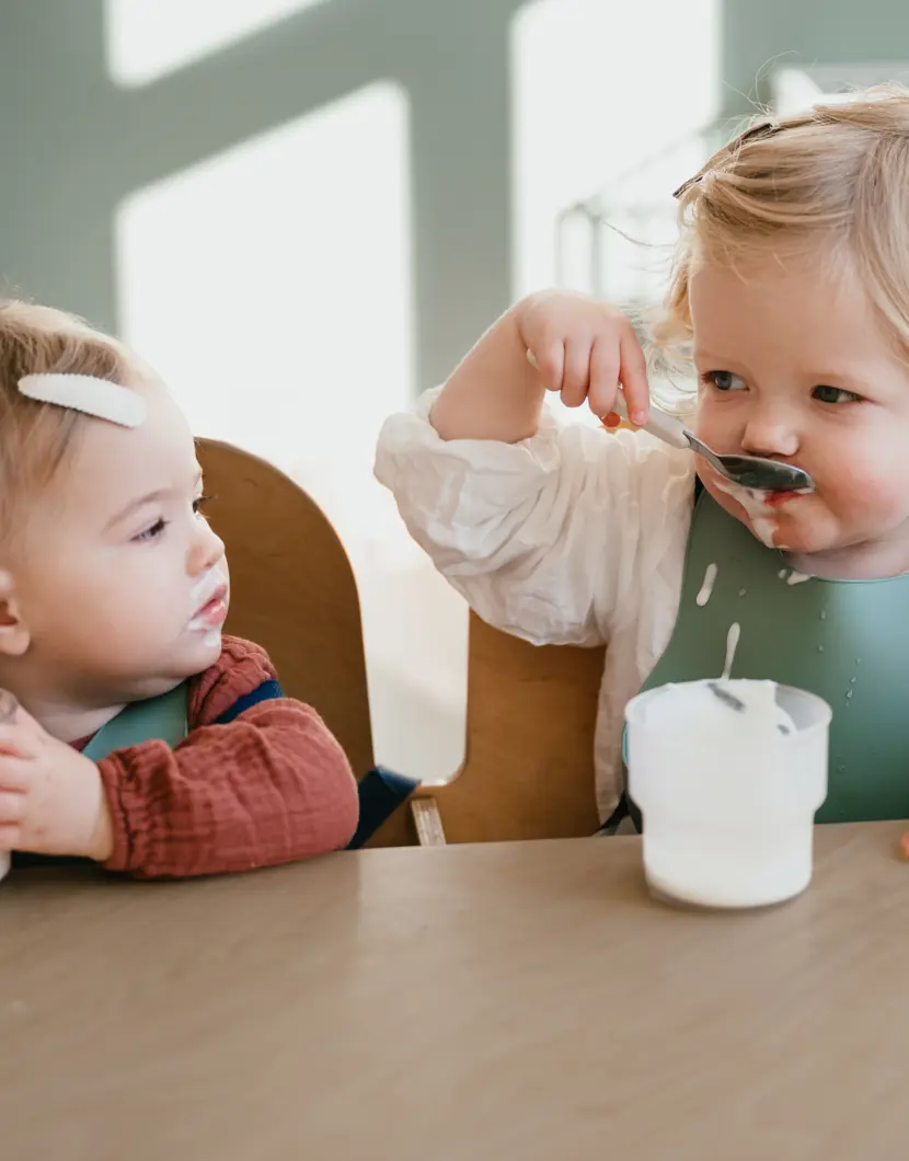 Twee kinderen eten yoghurt aan tafel