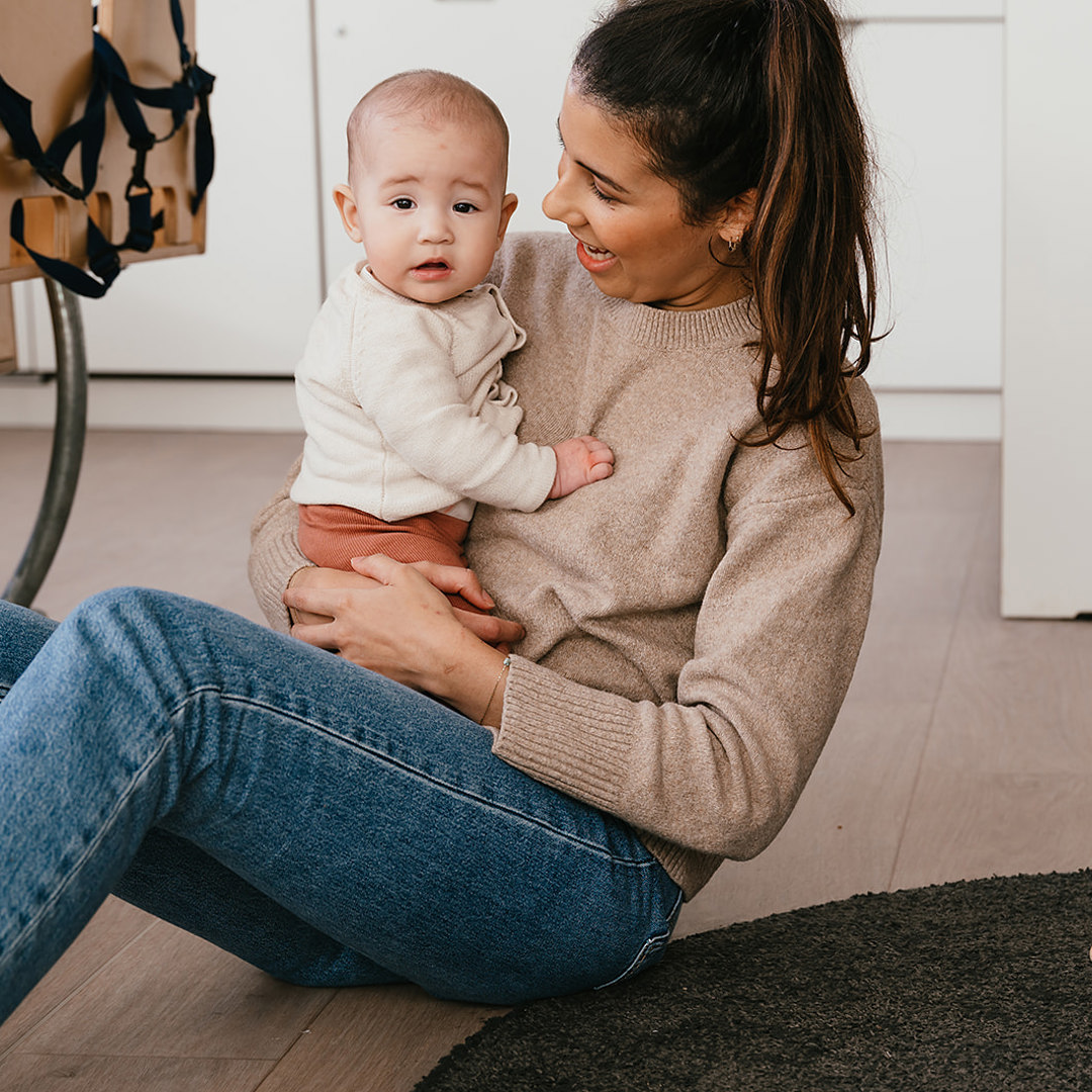 Vrouw zit met baby op de grond