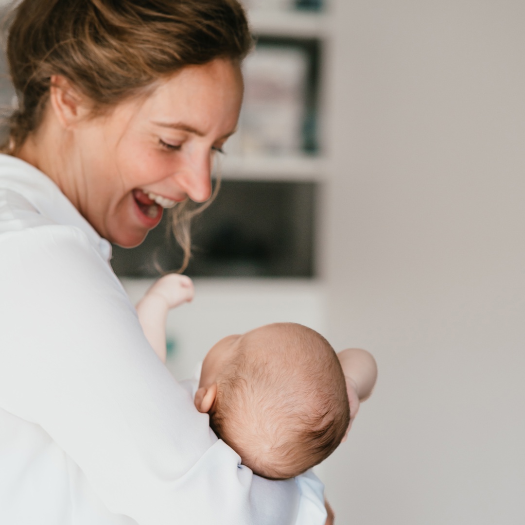 Vrouw houdt baby vast en lacht naar haar